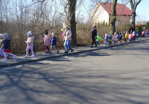 Dzieci wraz z paniami maszerują z panią Wiosną ulicami osiedla, śpiewają wiosenne piosenki.